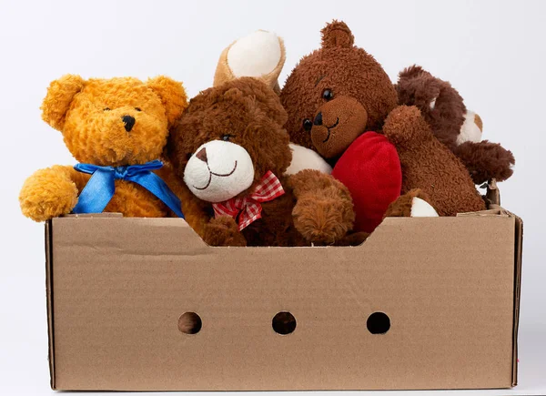 Caixa de papelão marrom com vários ursos de pelúcia, fundo branco — Fotografia de Stock