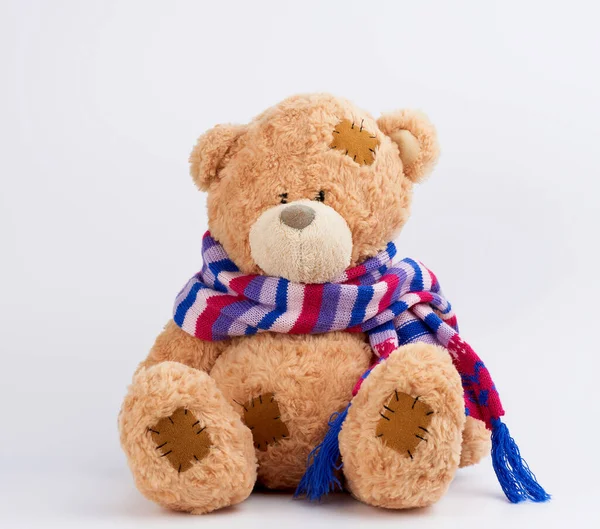 Lindo oso de peluche marrón con parches en una bufanda de punto de color si — Foto de Stock