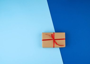 Kahverengi kraft kağıdına sarılı bir kutu ve kırmızı ince ipek bir R ile bağlanmış.