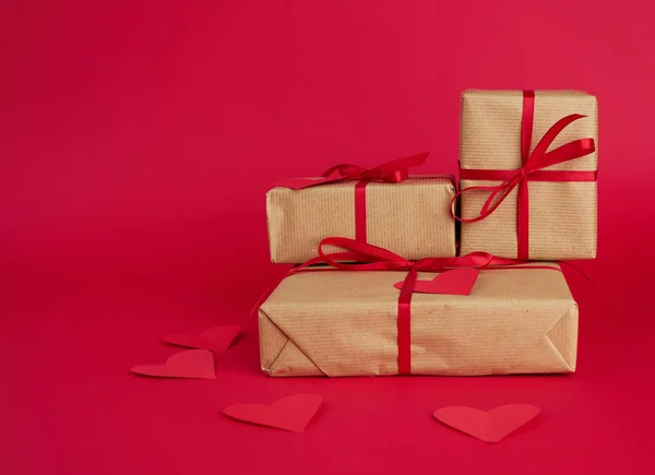 Pila de regalos envueltos en papel kraft marrón y atado con un rojo — Foto de Stock