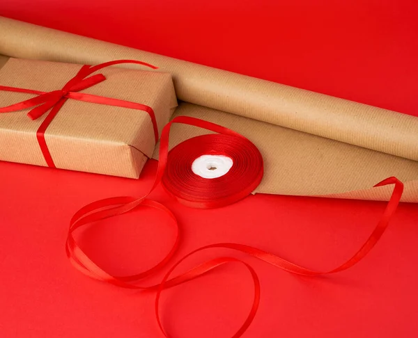 roll of brown paper for packaging, a reel of red ribbon and a wr