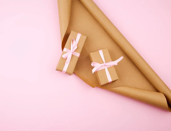 Papel kraft marrón, cajas de regalo embaladas y atadas con una cinta rosa —  Fotos de Stock