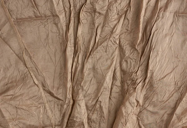 Textura zmačkané hnědé syntetické tkaniny se švy pro šití — Stock fotografie