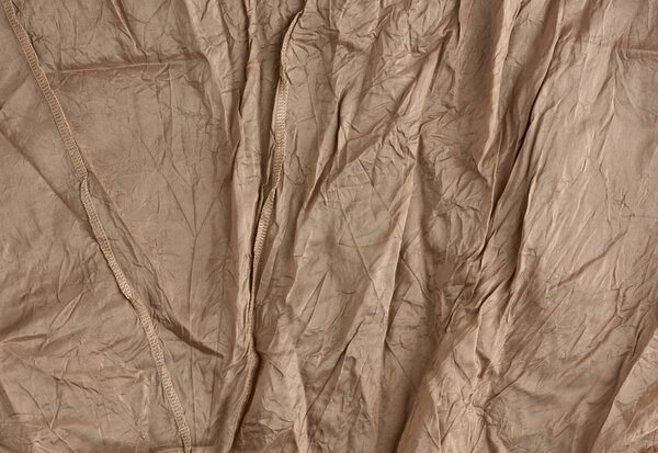texture of crumpled brown synthetic fabric with seams for sewing