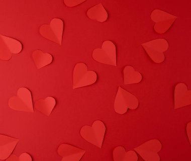 Kırmızı arka planda kırmızı kağıtlardan kesilen kalpler, şenlikli geri tepme