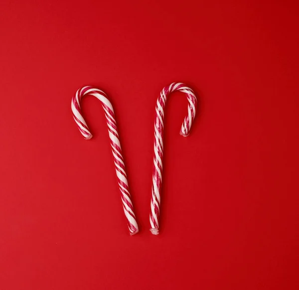 Red-white candy stick in transparent cellophane on a red backgro — Stok Foto