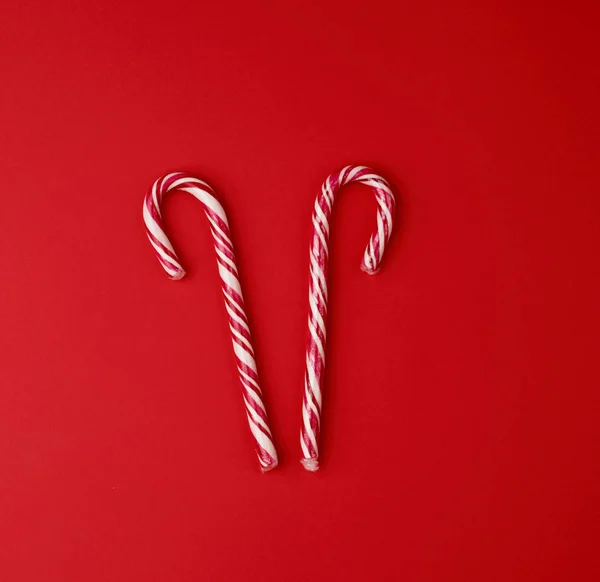 Red-white candy stick in transparent cellophane on a red backgro — Stock Photo, Image