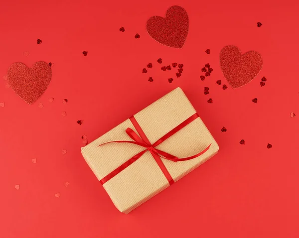 Box wrapped in brown kraft paper and tied with a red thin silk r — Stock Photo, Image