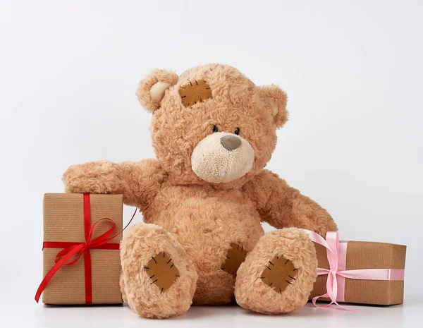 Gran oso de peluche beige con parches, una pila de regalos en cajas wra — Foto de Stock