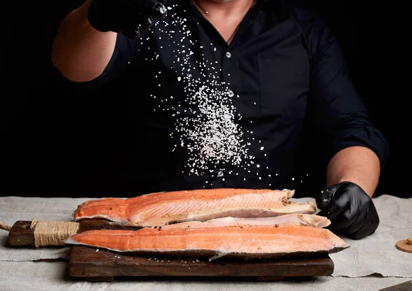 Chef in camicia nera e guanti in lattice nero prepara fil di salmone — Foto Stock