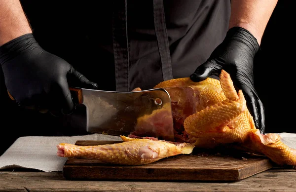 Koki berseragam hitam dan sarung tangan lateks memotong ayam mentah menjadi — Stok Foto