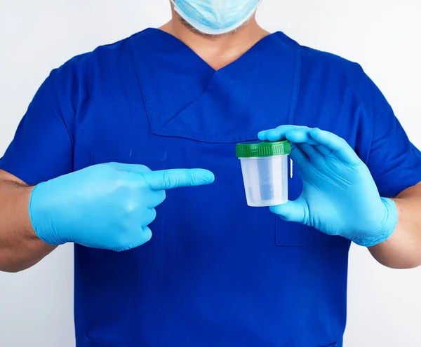 Doctor en uniforme azul y guantes de látex está sosteniendo un plas vacío —  Fotos de Stock