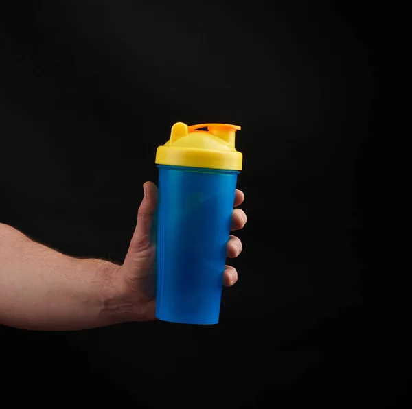 Adult male athlete with muscles holds a plastic bottle of water, — Stock Photo, Image