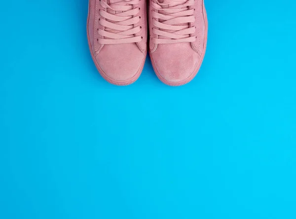 Paar sport roze sneakers met veters op een blauwe achtergrond — Stockfoto