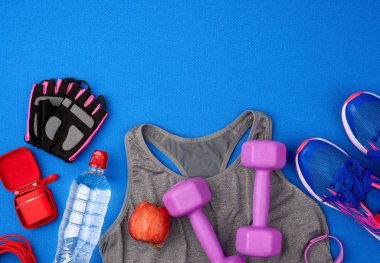 Plastik mor halterler, spor kıyafetleri, su, pembe spor ayakkabılar ve...