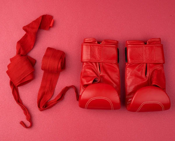 Pair of red leather boxing gloves and a textile red elastic band — Stock Photo, Image