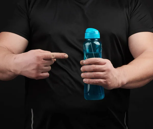 Atleta masculino adulto com músculos detém uma garrafa de plástico de água — Fotografia de Stock