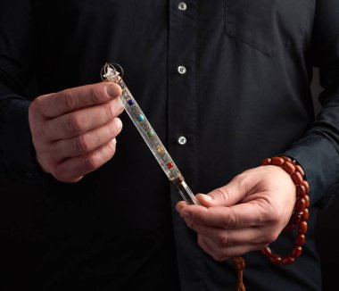 adult man in a black shirt holds a crystal chakra rod inlaid wit