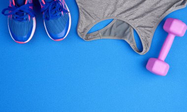 purple plastic dumbbell, gray sports shirt on a blue background