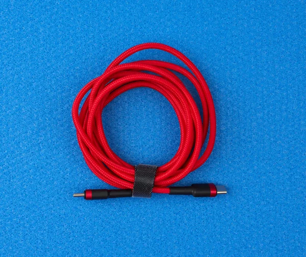 Изогнутый кабель для зарядки мобильных устройств в красную текстильную обертку — стоковое фото