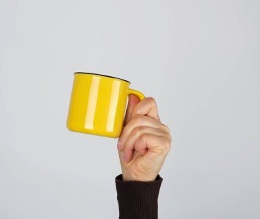 Beyaz arka planda bir kadının elindeki seramik bardak.