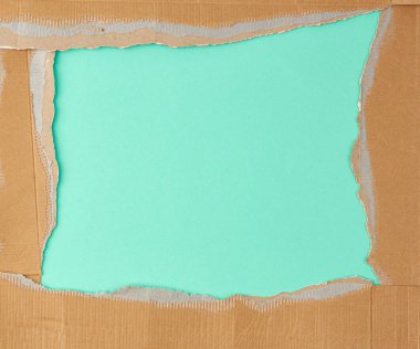 Yırtılmış kahverengi karton kağıdın kenarları yeşil bir sırtta.