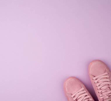 Mor arka planda bağcıkları olan pembe spor ayakkabıları.