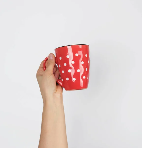 Taza de cerámica roja en una mano femenina sobre un fondo blanco — Foto de Stock