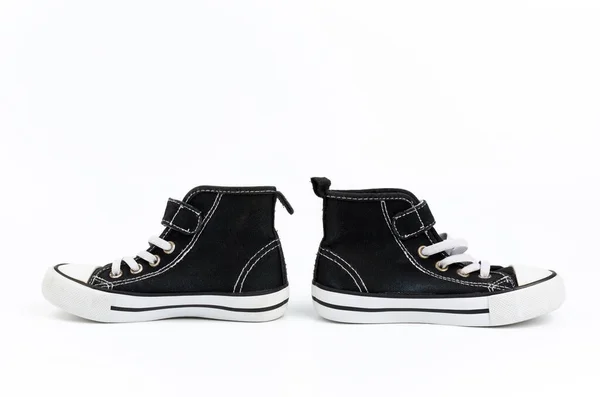 Svarta textila sneakers med vita bundna skosnören på vit rygg — Stockfoto