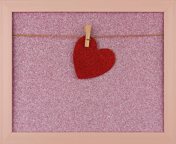 Red shiny paper heart hanging on a rope in a pink frame — Stock Photo, Image