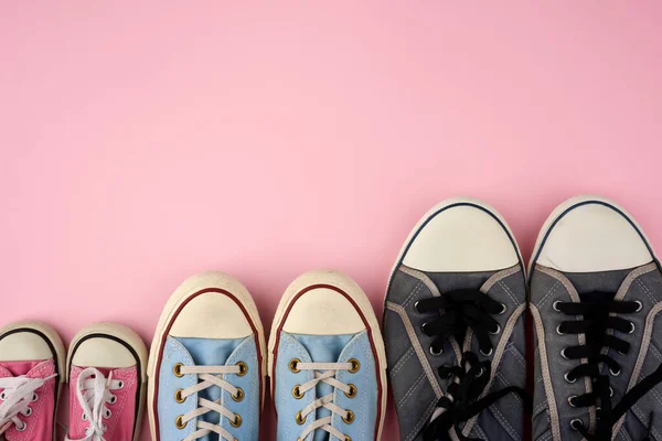 Veel van textiel gedragen sneakers van verschillende maten op een roze backgr — Stockfoto