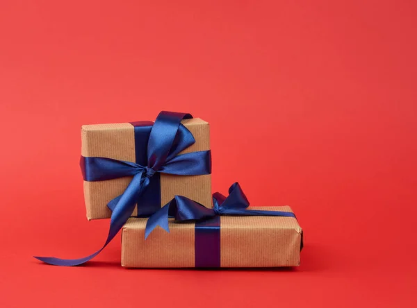 Stack of gifts wrapped in brown kraft paper and a silk blue ribb — 스톡 사진