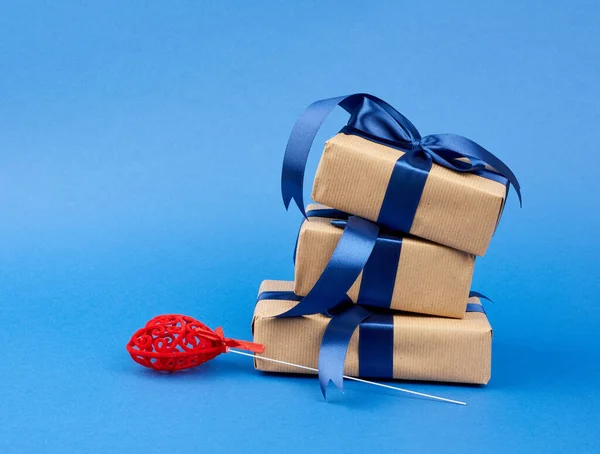 Pilha de presentes embrulhados em papel kraft marrom e uma fita azul de seda — Fotografia de Stock