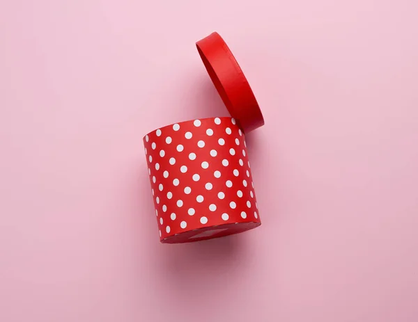 Caja redonda de cartón rojo con lunares blancos sobre fondo rosa — Foto de Stock