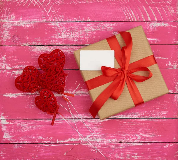 Caja rectangular con un regalo atado con una cinta de seda roja y rojo — Foto de Stock