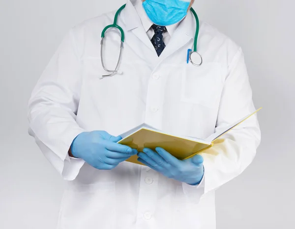 Médico con una bata blanca, guantes estériles de látex azul sostiene una abierta — Foto de Stock
