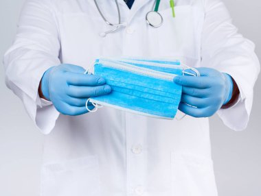Beyaz önlüklü doktor, mavi lateks steril eldivenli tekstil sahibi. 