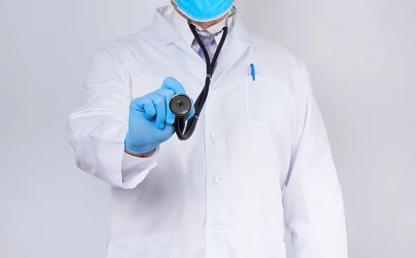 doctor in a white coat and tie holds in his hand a black phonend