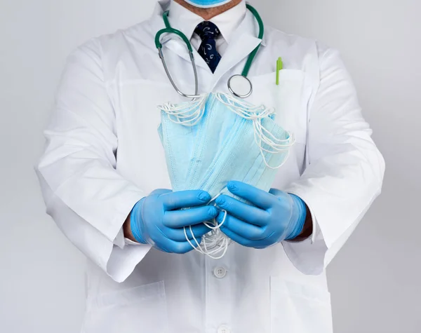 Arzt im weißen Mantel, blaue Latex-sterile Handschuhe halten Textilien — Stockfoto