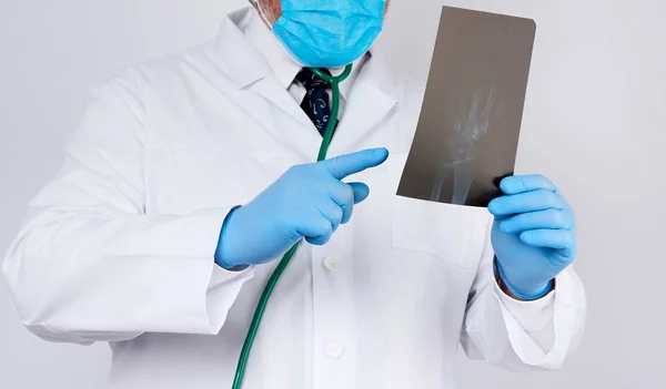 Médico em um casaco branco e luvas de látex azuis — Fotografia de Stock