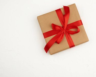 Kare kutu kahverengi kraft kağıdına sarılmış ve kırmızı ipek ile bağlanmış.