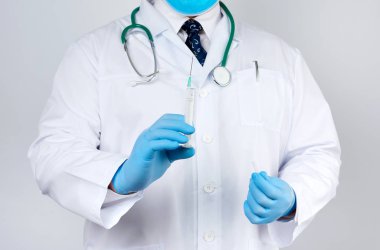 Beyaz önlüklü ve kravatlı erkek doktor ayakta duruyor ve elinde plastik bir s var.