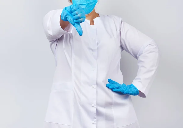 Sanitäterin in weißem Mantel und Maske, mit blauem medizinischen Latex — Stockfoto