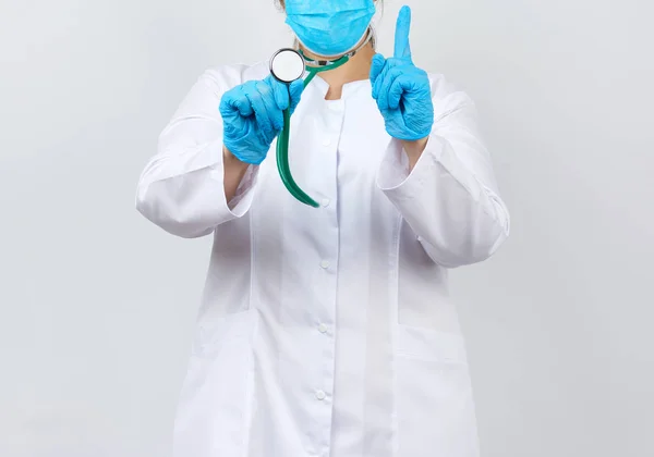Sanitariuszka w białym płaszczu i masce, ubrana w niebieski medyczny lateks — Zdjęcie stockowe