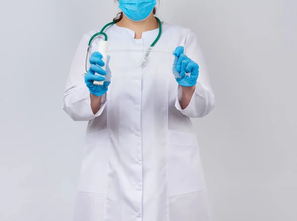 Mulher médica em casaco branco e máscara detém uma bandagem de gaze torcida — Fotografia de Stock
