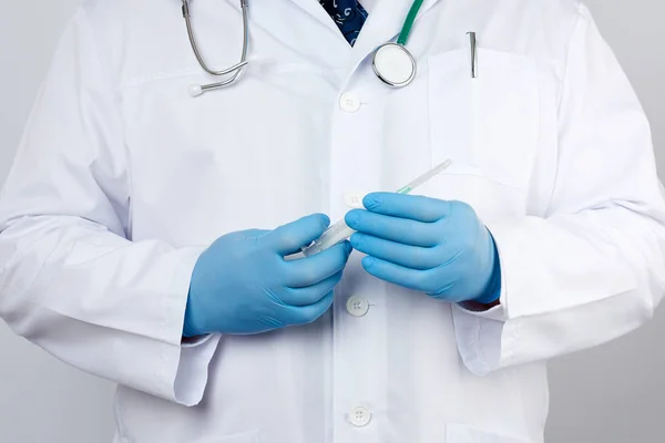 Doctor masculino con una capa blanca y corbata se para y sostiene una s de plástico —  Fotos de Stock