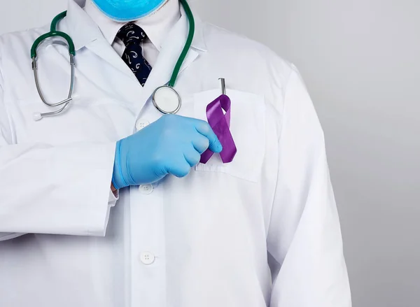 Médico masculino con un abrigo blanco y corbata se para y sostiene un si púrpura — Foto de Stock