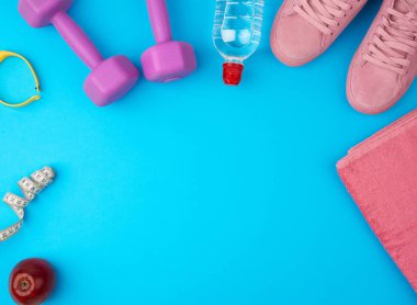 Plastik mor halterler, spor kıyafetleri, su, pembe spor ayakkabılar. 