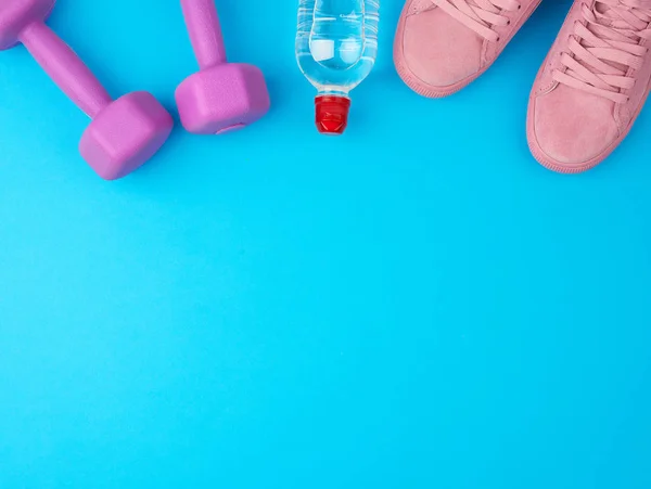 Lila hantlar och en genomskinlig plastflaska vatten, rosa sko — Stockfoto