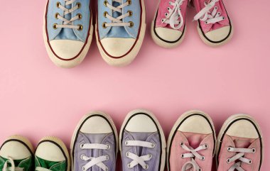 Pembe arka plan, üst görünüm, konsept, aile ve takım, arkadaşlık, kopyalama alanı üzerinde farklı boyutlarda çok renkli iyi giyimli tekstil ayakkabıları.